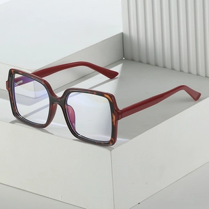 Fashionable oversized square red eyeglasses with tortoiseshell pattern on white stand