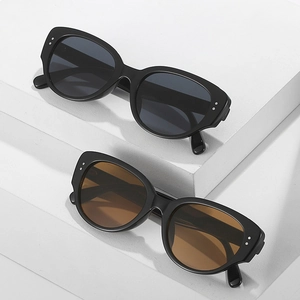 Retro cat-eye sunglasses with thick black frames and silver rivet accents on white steps