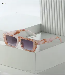 Detail of pink marble texture square sunglasses with gradient purple lenses and gold trim