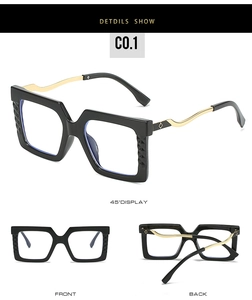 Detail view of large square black and gold glasses with wavy metal temples and texture