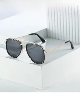 Détail de lunettes de soleil carrées en métal doré avec verres gris sur fond blanc