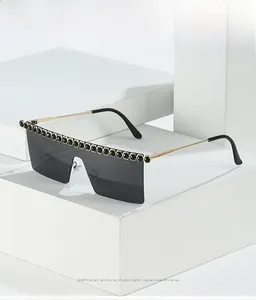 Détail de lunettes de soleil carrées avec cristaux noirs et branches dorées fines