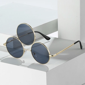 Three-lens steampunk sunglasses with gold metal frame and dark round lenses on stone