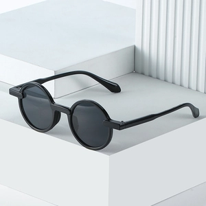 Modern vintage round sunglasses with black frames on a minimalist white display