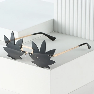 Golden metal leaf-shaped sunglasses with dark grey lenses and minimalist white background