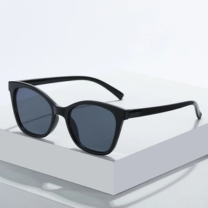Lunettes de soleil œil de chat noir classique avec verres foncés sur socle blanc