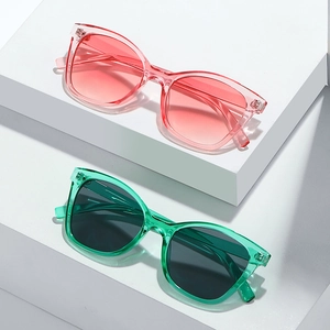Lunettes de soleil œil de chat chic avec montures rose et vert transparent sur socle
