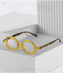 Detail of round acetate eyeglasses with amber frame and tortoiseshell temples on geometric base