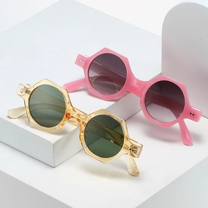 Lunettes de soleil polygonales rétro avec montures rose et ambre sur socles blancs