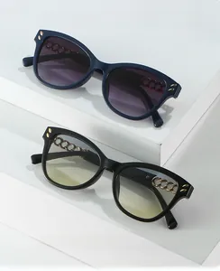 Detail view of cat eye sunglasses with gold chain temples and rivet accents on frames