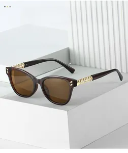 Detail of trendy cat-eye sunglasses featuring golden chain temples and brown lenses
