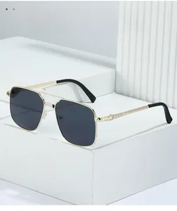 Détail de lunettes de soleil en métal doré avec branches gravées et verres foncés