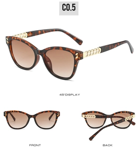 Detail view of tortoiseshell cat-eye sunglasses with gold metal chain accent and brown lenses