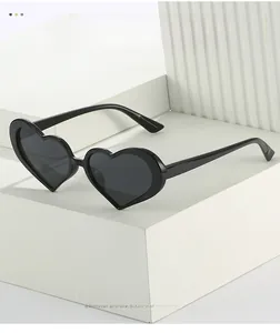 Detail of heart-shaped sunglasses with black frames on a white geometric display stand