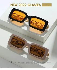 Detail of square sunglasses featuring bold gold chain temples and vibrant tinted lenses
