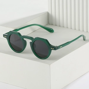 Retro emerald green geometric round sunglasses with gold rivets on white steps