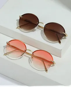 Detail of round rimless sunglasses with gradient lenses and gold metal frames on white steps