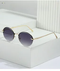 Detailed view of rimless oval sunglasses with grey gradient lenses and gold metal frames