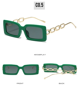 Close-up of square green sunglasses featuring decorative gold chain temples and gray lenses