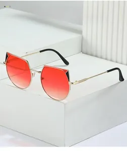 Detail view of irregular gold metal sunglasses with red gradient lenses on stone