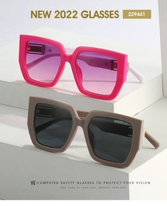 Detail of square oversized sunglasses with gold metal accents on white pedestals