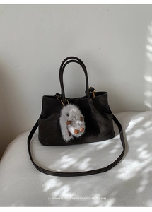 Detail of dark brown matte leather tote bag with soft plush rabbit charm and handle