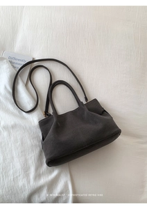 Macro view of dark grey matte shoulder bag with minimalist double stitching on soft fabric
