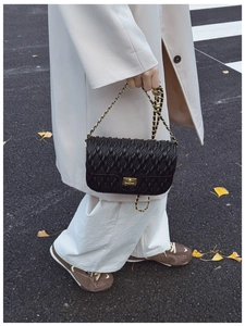 Détail du sac matelassé noir avec fermoir doré et bandoulière en chaîne élégante