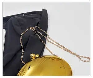 Detail of elegant gold evening bag with metallic chain strap and sphere clasp
