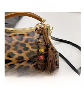 Détail d'un sac léopard avec poignée en bois, fermoir doré et pompon perlé élégant