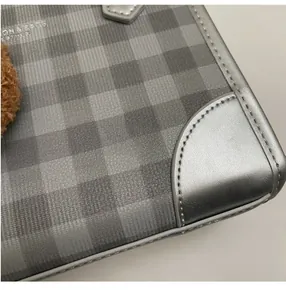 Macro shot of grey plaid fabric and silver leather piping with refined stitching details