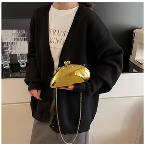 Detail of mirror gold clutch bag with metal chain strap held by a fashion model