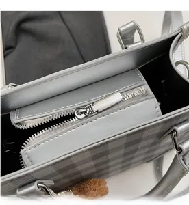 Detail of smooth metal zipper and classic grey plaid pattern on the handbag