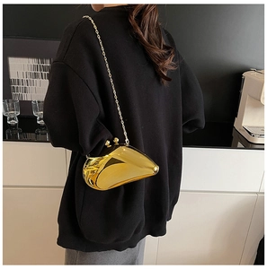 Close-up of a gold geometric clutch with metallic chain strap worn over a black hoodie