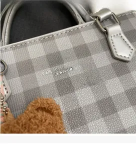 Detail of plaid fabric texture and silver leather handle with cute bear charm