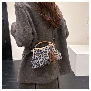 Détail d'un sac à motif léopard avec fermoir doré kiss-lock et pendentif à franges