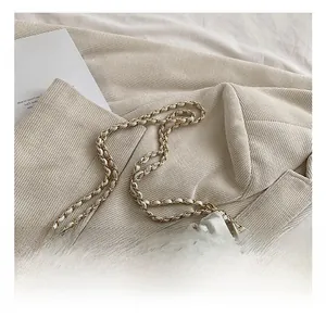Detail of cream quilted bag with gold chain strap and decorative metallic ball charm