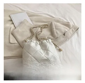 Detail of white quilted drawstring bag with lychee texture and golden chain strap