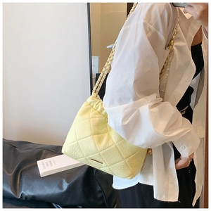 Detail of light yellow quilted crossbody bag with gold chain strap and metal trim