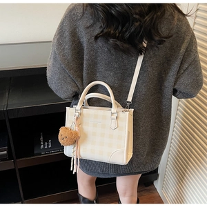 Detail of checkered crossbody bag with plush bear charm and ZISHUAN & BAGS lettering
