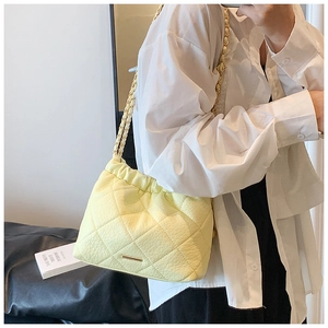 Close-up of a yellow quilted chain bag with drawstring closure and golden metal hardware