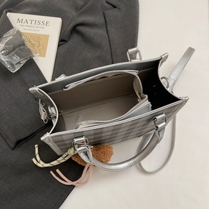 Top view of plaid crossbody bag interior with silver handles and decorative pompom charm