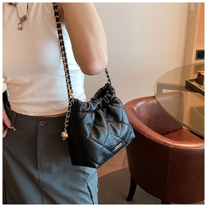 Close-up of black quilted bucket bag with gold chain strap and drawstring closure