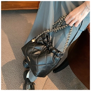 Detail of black quilted leather bag with gold chain strap and metal ball adjuster