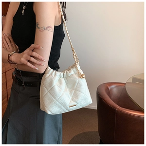 Lifestyle shot of white quilted crossbody bag with gold chain and leather woven strap