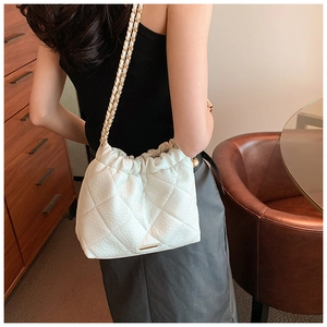 Detail of white quilted leather chain bag with elegant fold design on a model