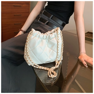 Detail of white quilted chain bag with elegant gold hardware and drawstring design