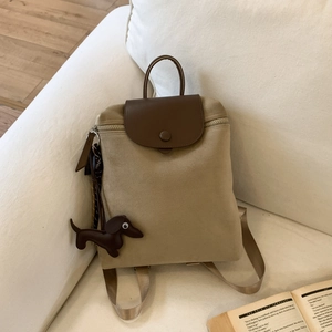 Detail of vintage canvas backpack with brown leather trim and a dachshund bag charm