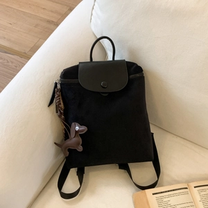 Detail of minimalist black canvas backpack with leather flap and brown dachshund charm