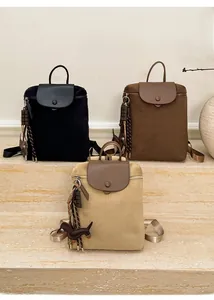 Three minimalist casual backpacks in black, dark brown and beige on stone steps